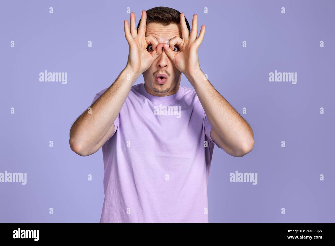 Young handsome man doing gesture like binoculars Stock Photo