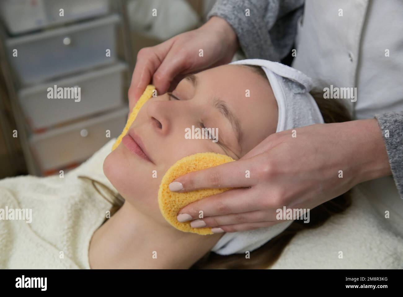 Dermatologist preparing woman's face skin for treatment. Process of cleaning, peeling and exfoliation. Stock Photo