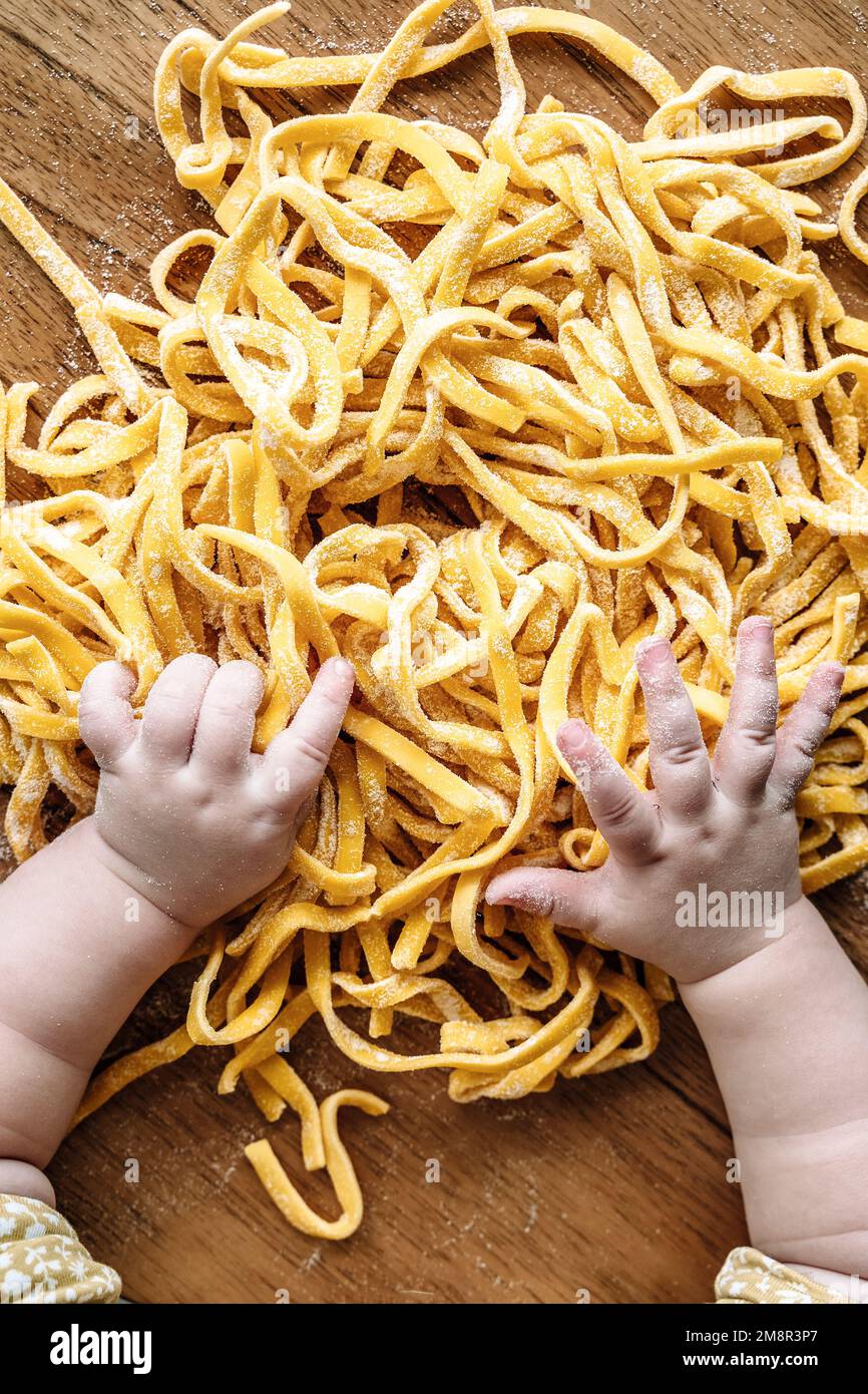 Pasta and child. Baby cooks Italian fresh pasta in the home kitchen. Food and kids concept. High quality photo Stock Photo