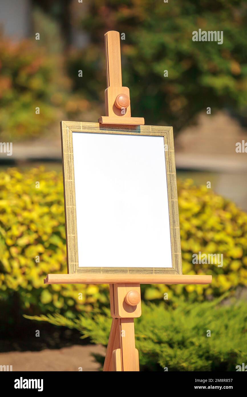 White empty mockup display board on wooden easel outdoors Stock Photo