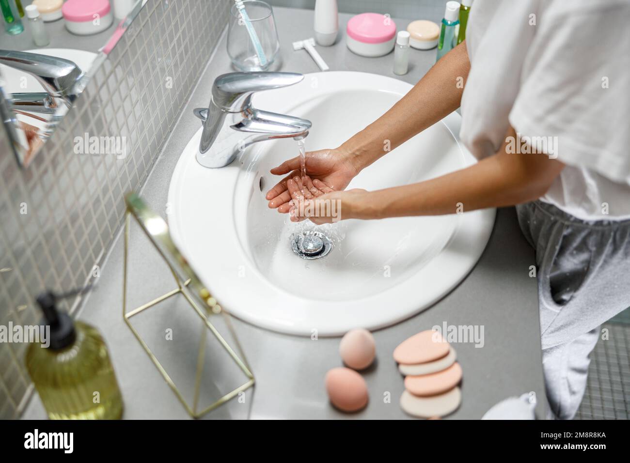 Cropped image of young woman washing her hands in the bathroom at home ...
