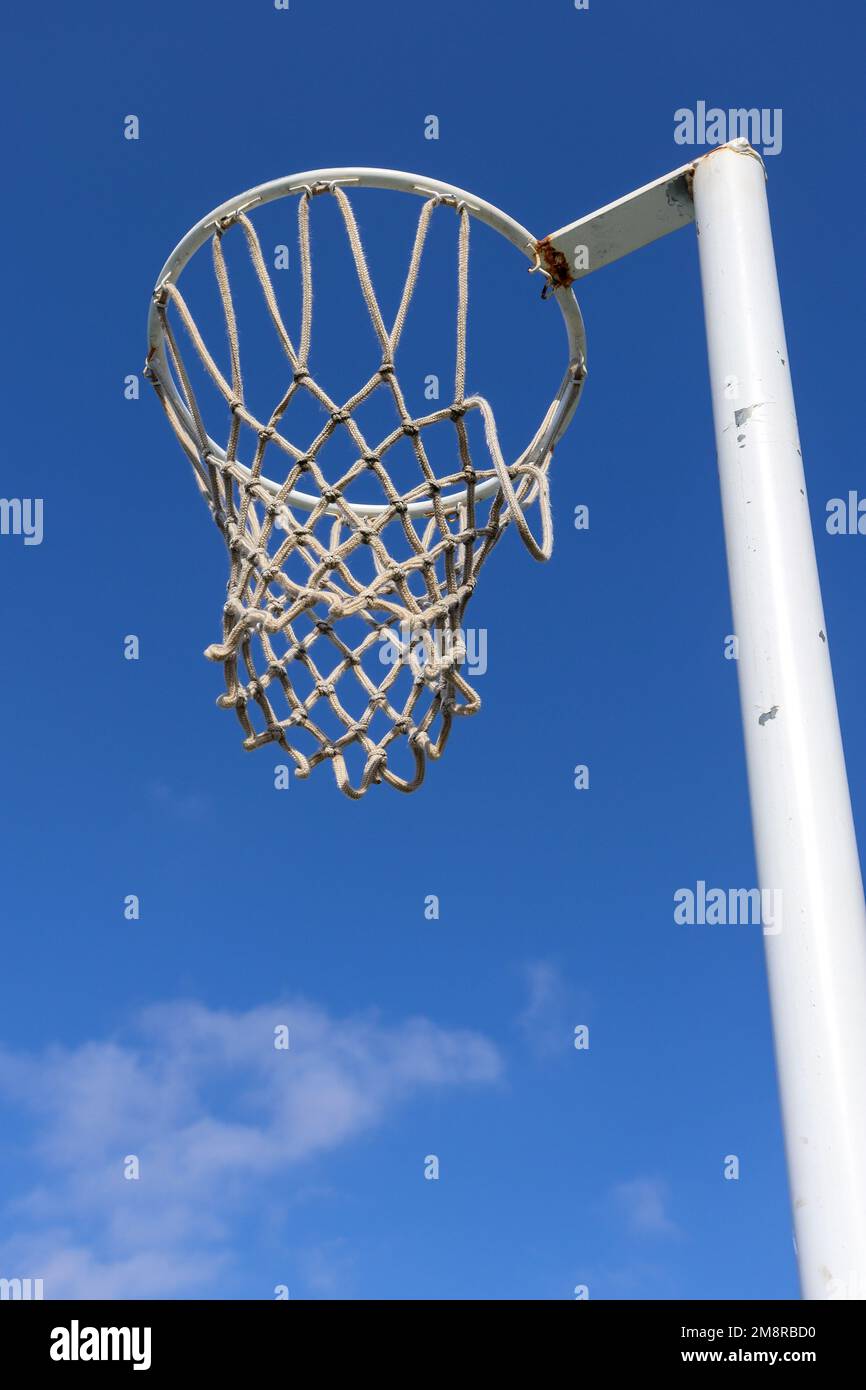 A vertical shot of a netball hoop against a blue sky Stock Photo