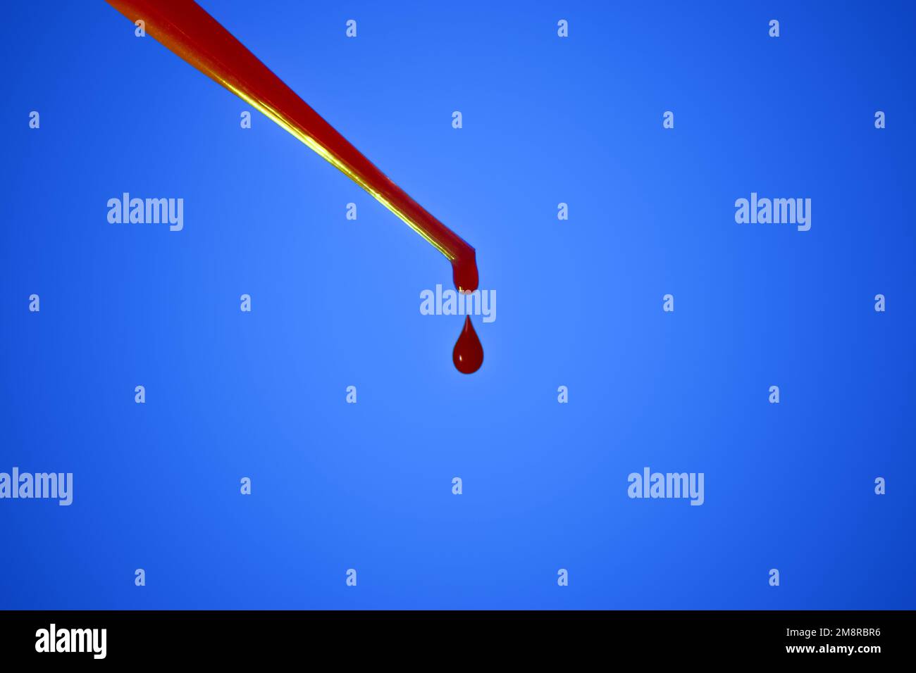 A drop of blood. Pipette. On a blue background. Dripping red liquid. A