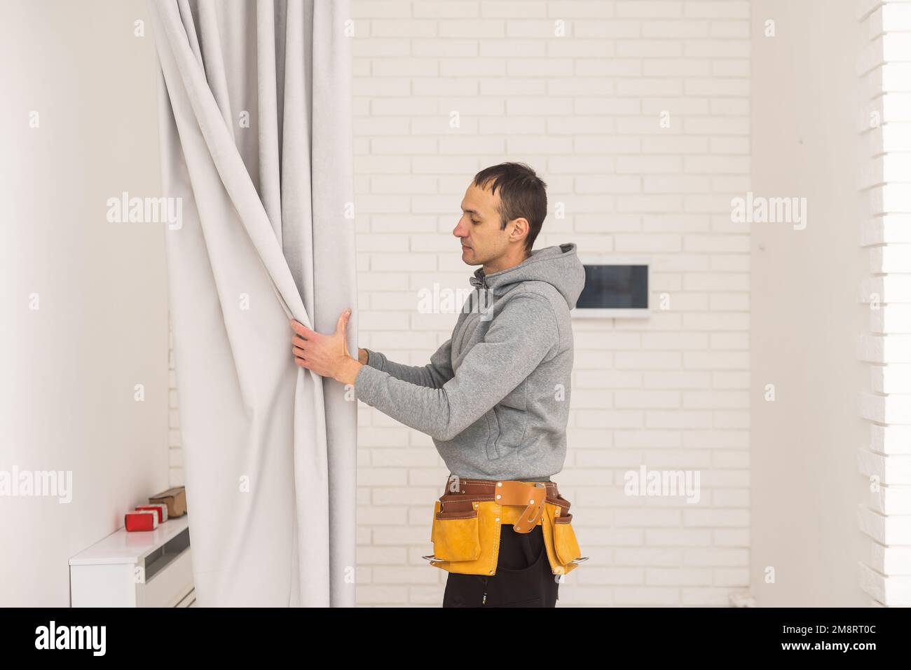 Young man installing curtains over window Stock Photo