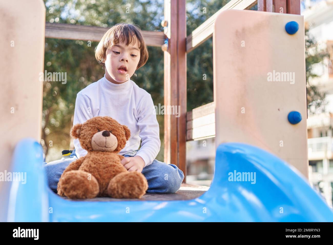 Down syndrome kid playing with teddy bear on slide at park Stock Photo Alamy