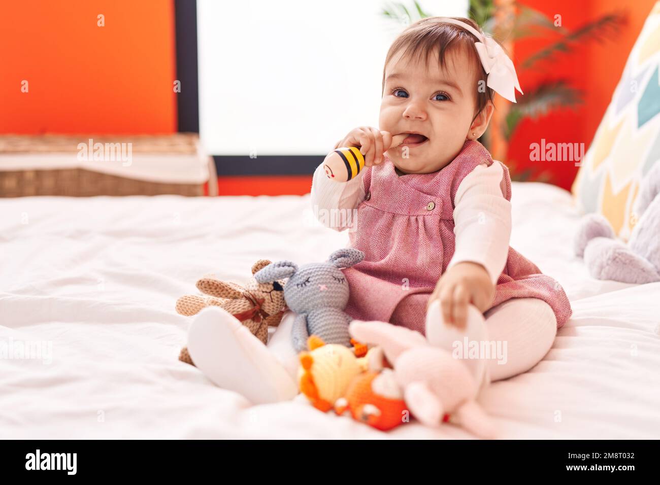 Adorable hispanic baby bitting maraca sitting on bed at bedroom Stock ...