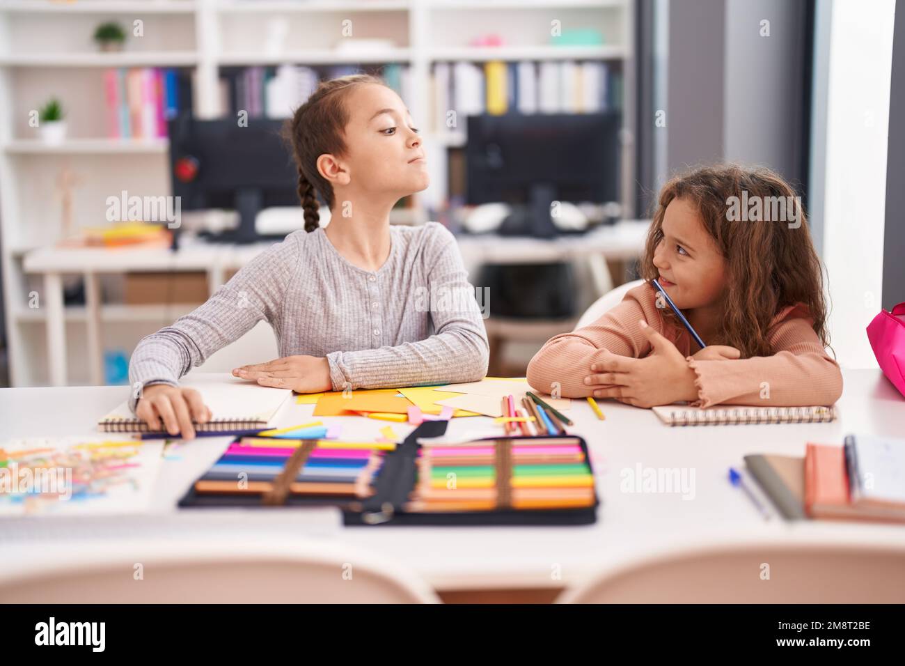 Two kids students sitting on table drawing on notebook paper at ...