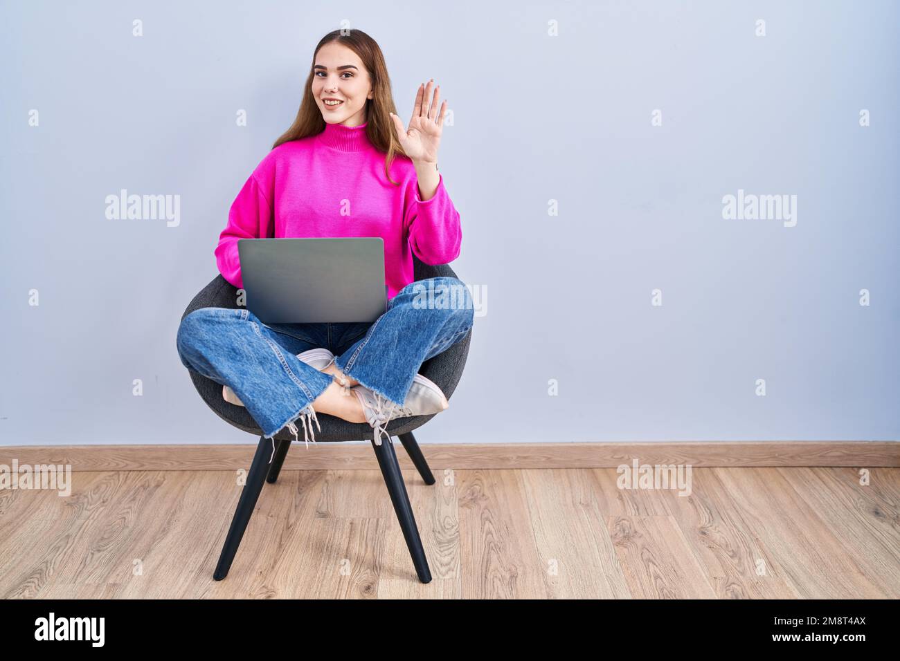 Young hispanic girl working using computer laptop waiving saying hello ...