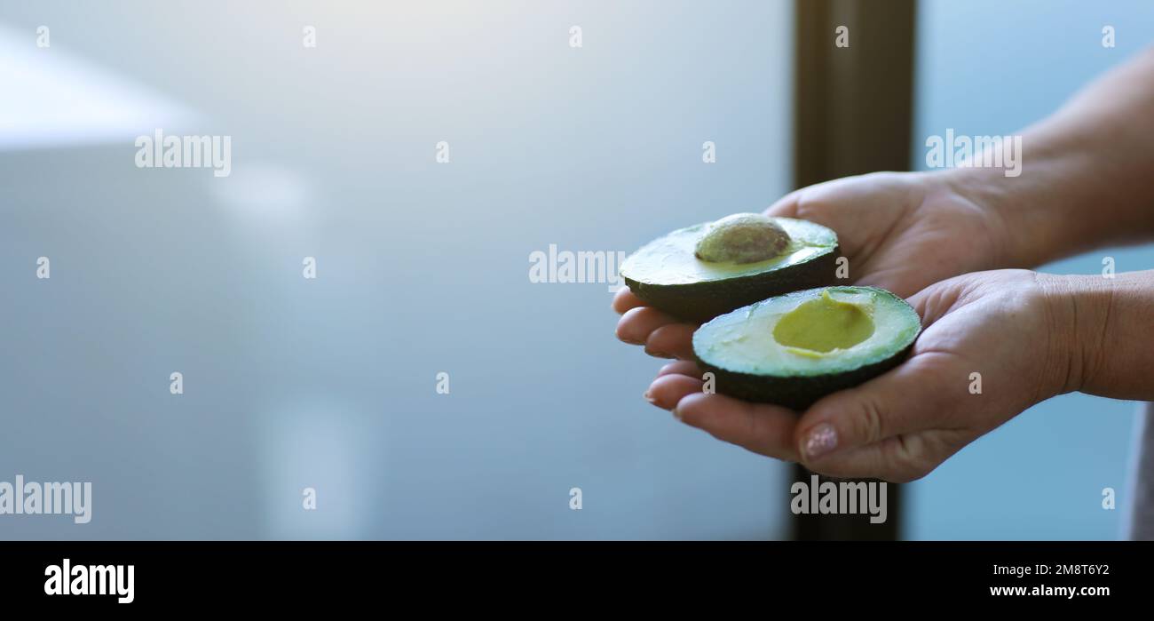 Unrecognised mature woman with fresh organic avocado fruit in hands for skincare, beauty and cosmetic wellness. Healthy lifestyle, healthy alkaline food and dieting concept. loosing weight.Copy space Stock Photo