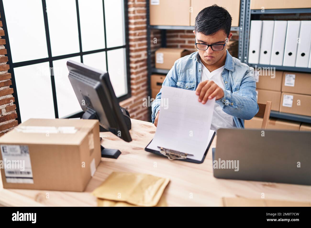 Down syndrome man ecommerce business worker reading document at office Stock Photo