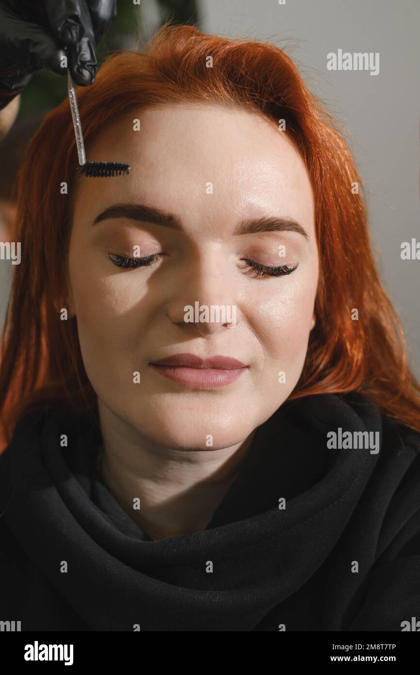 Eyebrows makeup. Face closeup of beautiful woman having brows correction in beauty salon