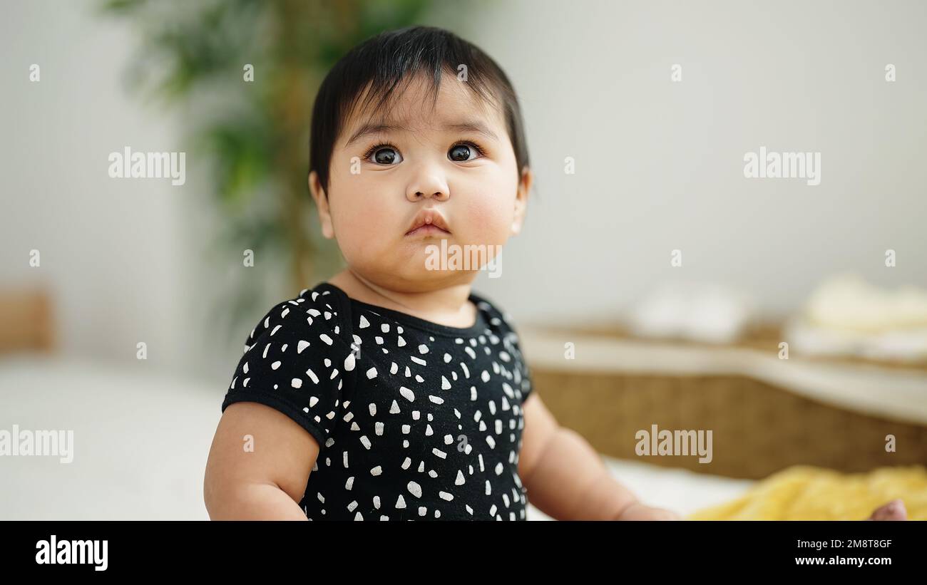 Adorable hispanic baby sitting on bed at home Stock Photo - Alamy