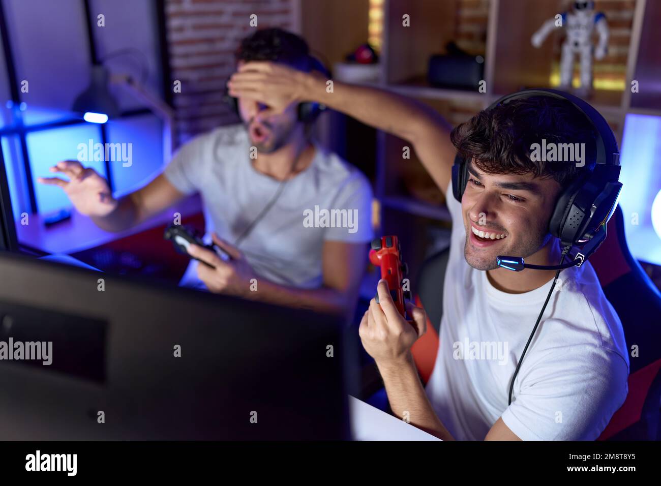 Two hispanic men streamers playing video game covering eyes cheating at