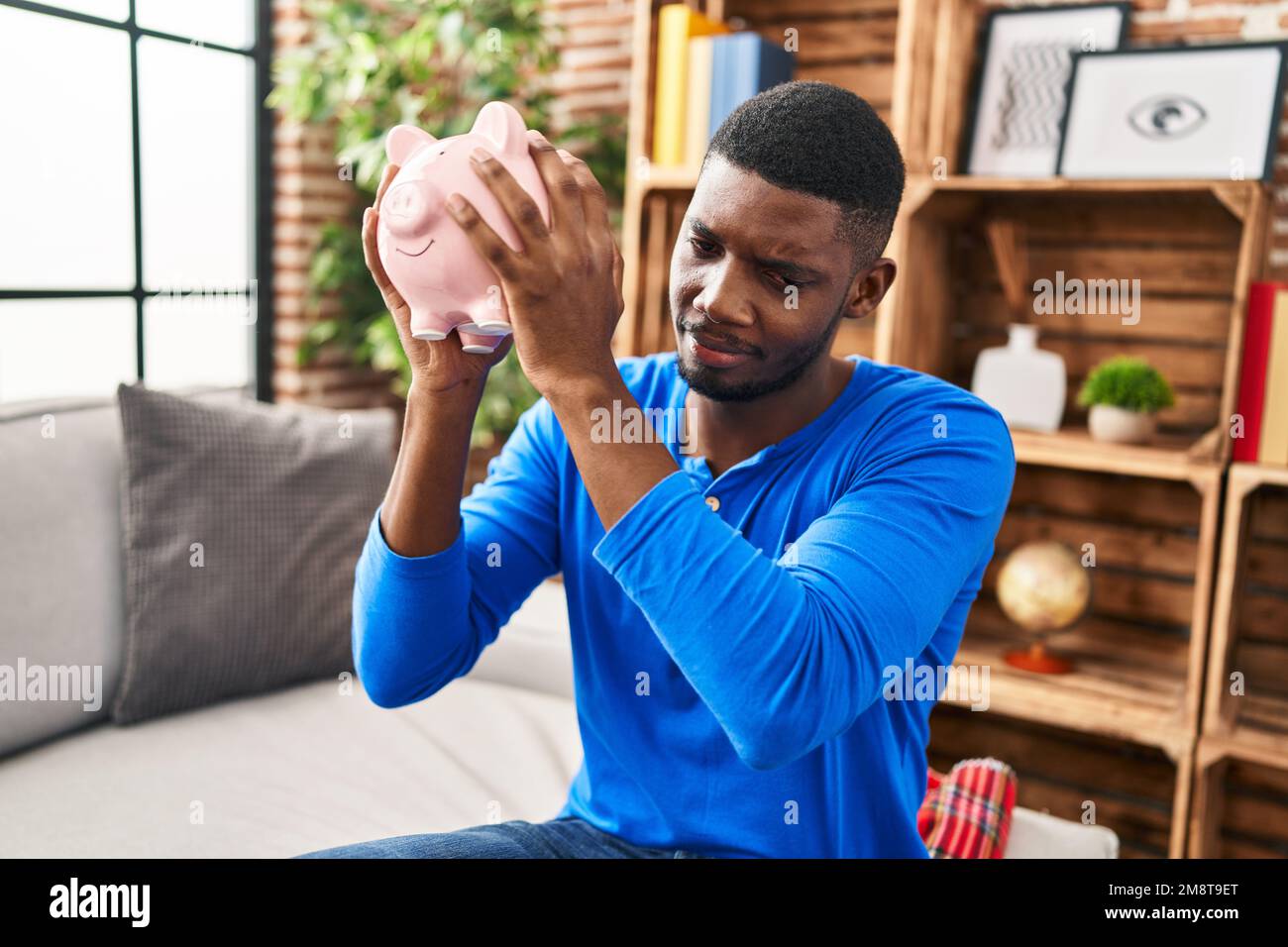 Young man worried piggy bank hi-res stock photography and images - Alamy