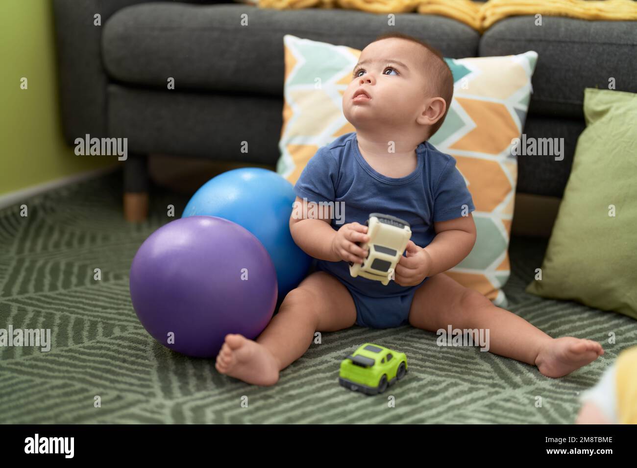 Adorable chinese toddler playing with cars toys sitting on floor at home Stock Photo