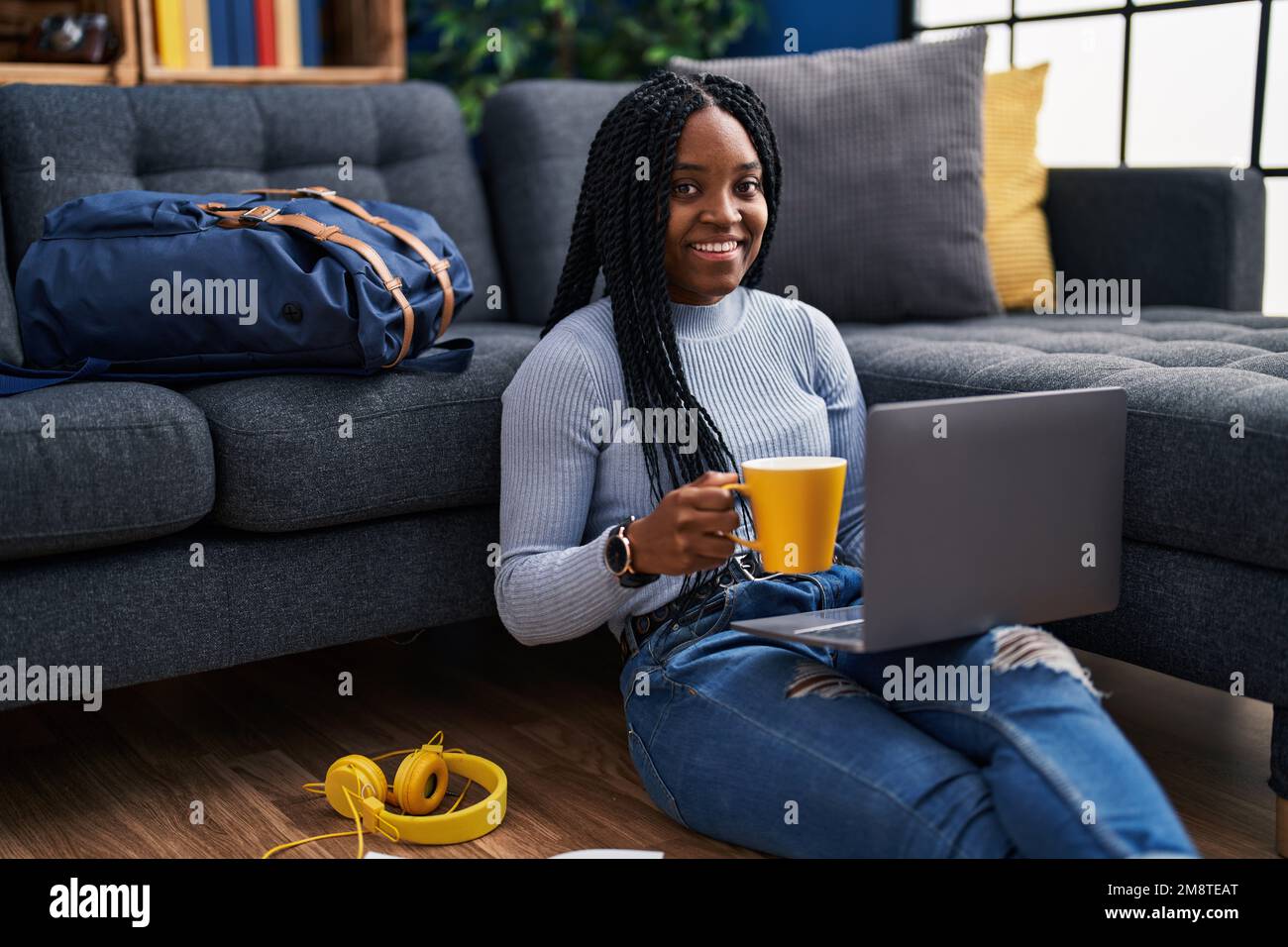 African american woman student using laptop drinking coffee at street ...