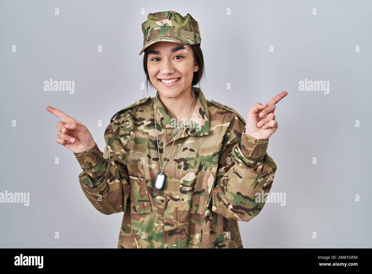 Young south asian woman wearing camouflage army uniform smiling confident pointing with fingers to different directions. copy space for advertisement Stock Photo