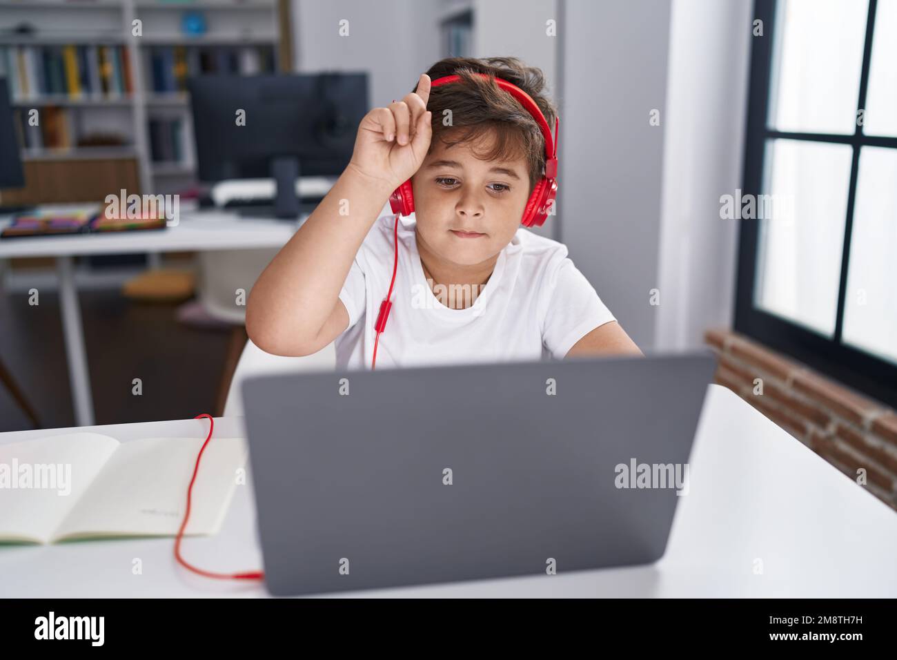 Adorable hispanic boy student using computer having long distance ...