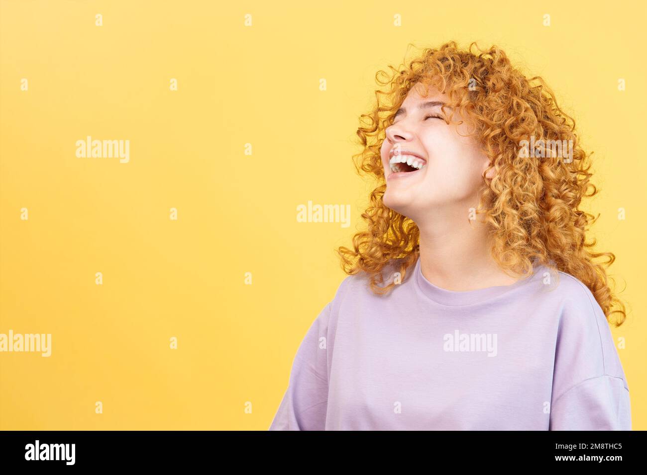 Woman with curly hair and casual clothes laughing Stock Photo