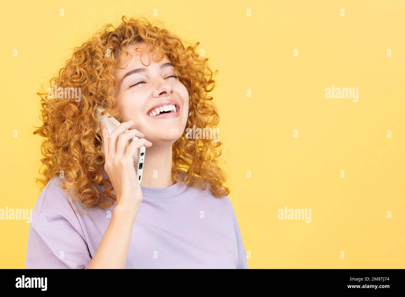 Woman talking to the mobile while smiling with eyes closed Stock Photo
