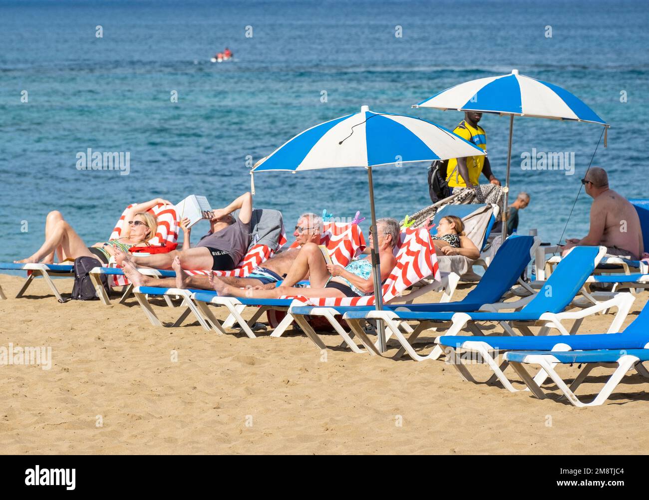 Las Palmas, Gran Canaria, Canary Islands, Spain. 15th January 2023.  Tourists, many from the UK, bask in glorious sunshine on the city beach in Las Palmas. Credit: Alan Dawson/Alamy Live News Stock Photo