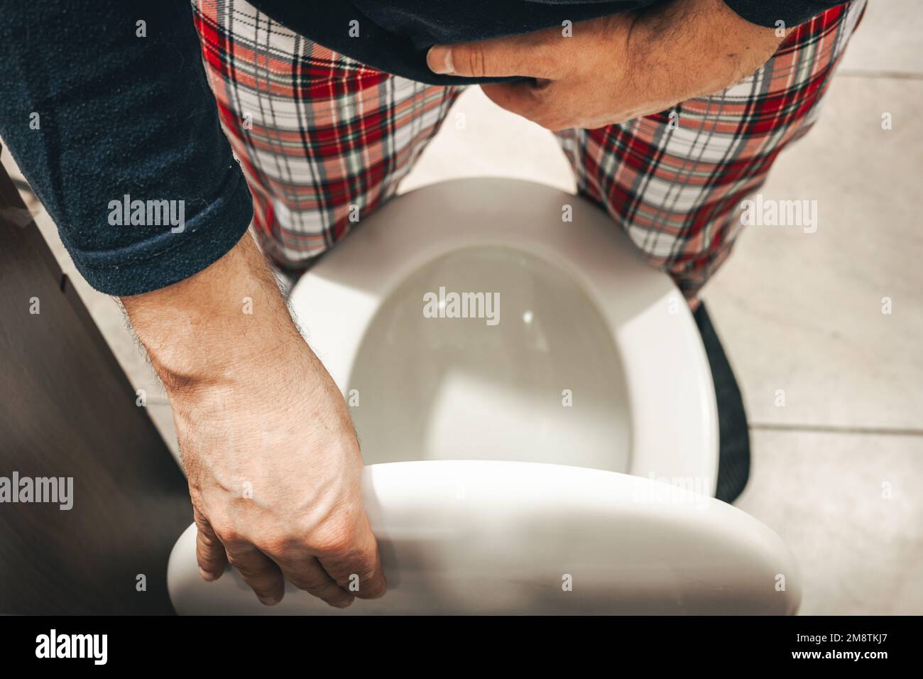Urination problem, A man in pajamas in the toilet squeezes his crotch