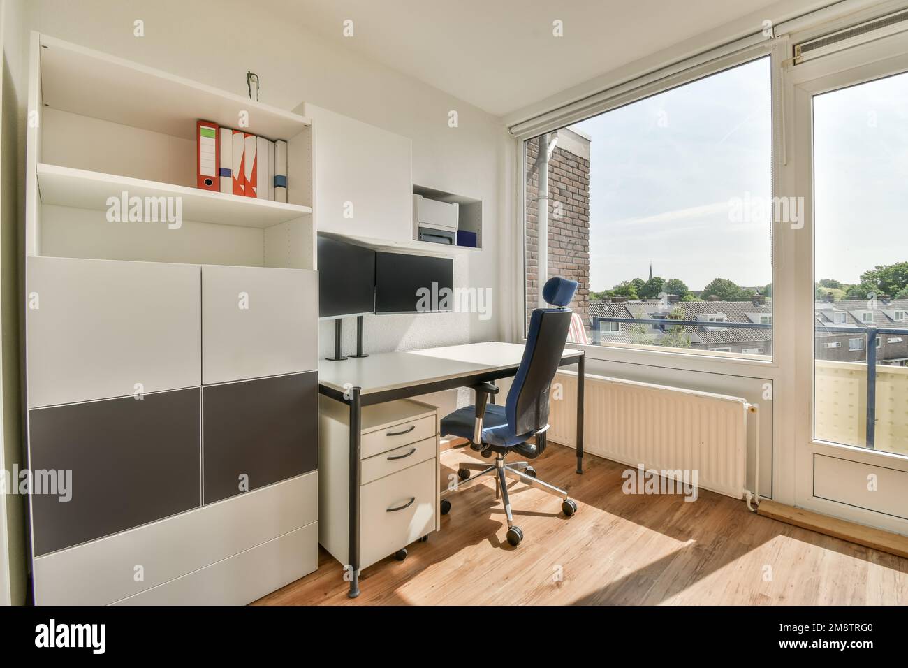 an office space with a desk, chair and computer monitor on the wall in front of the window