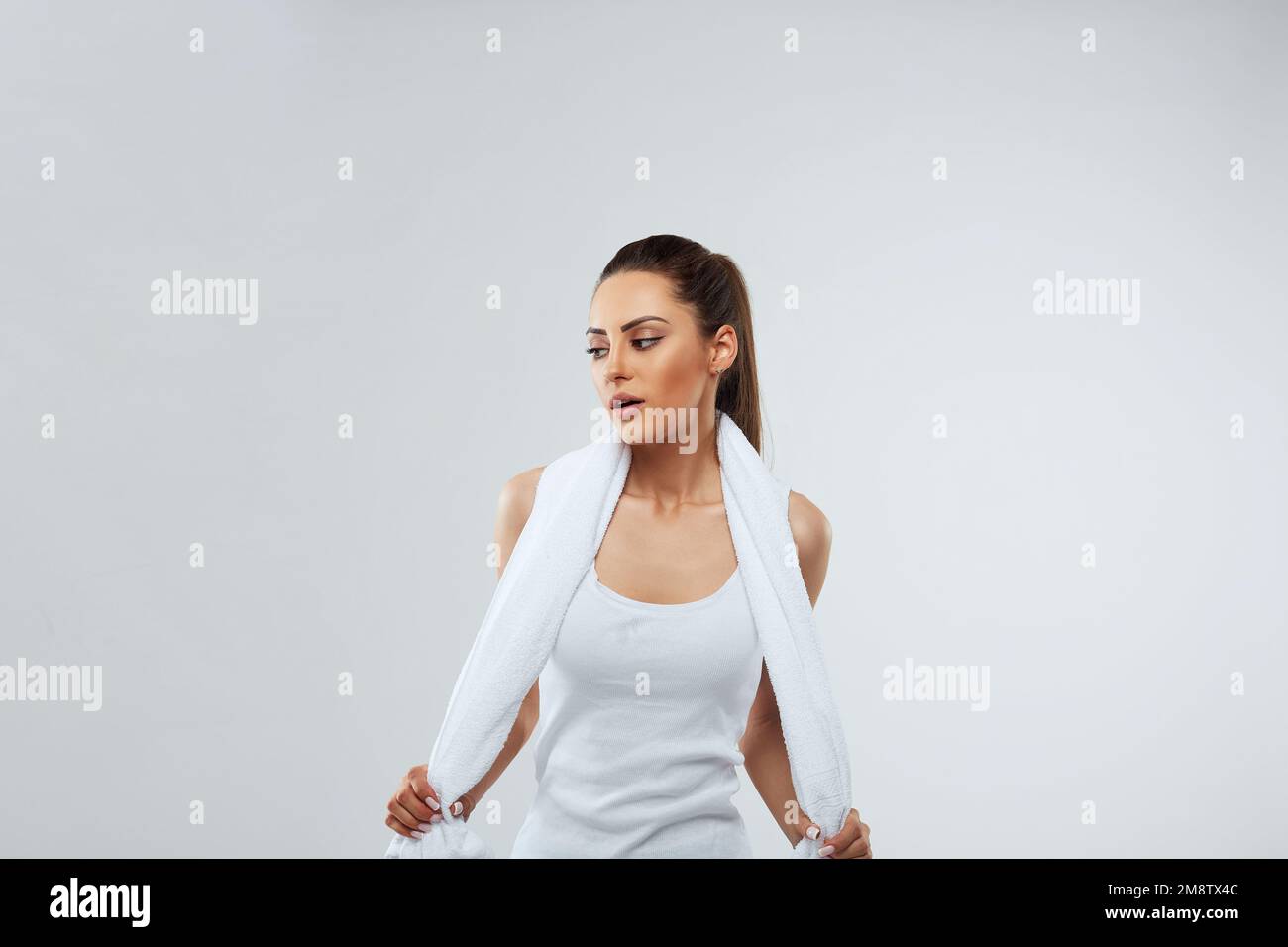Healthy beautiful sportswomen wearing tracksuit with towel looking isolated over gray background Stock Photo
