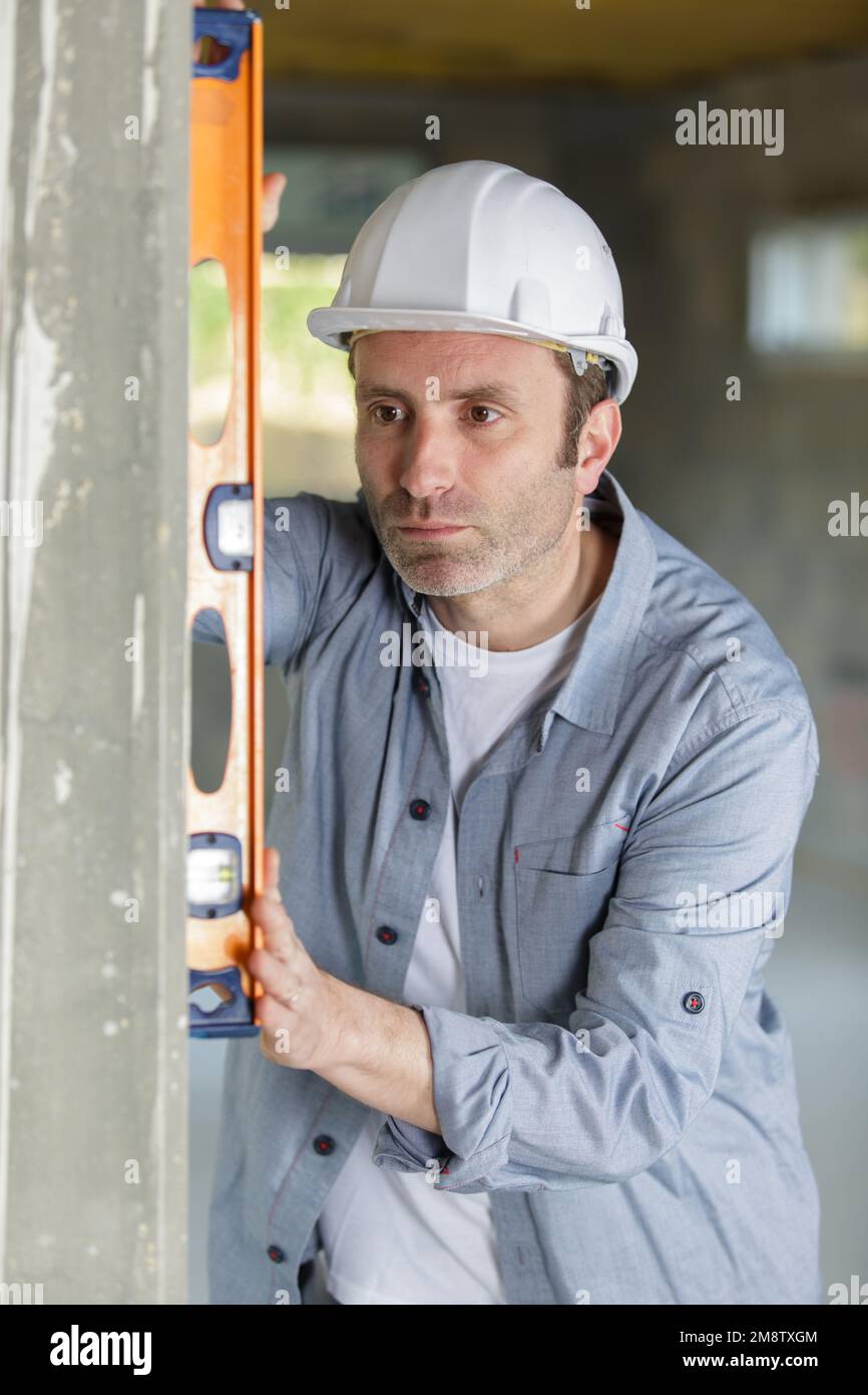 mature worker using spirit level on a concrete wall Stock Photo