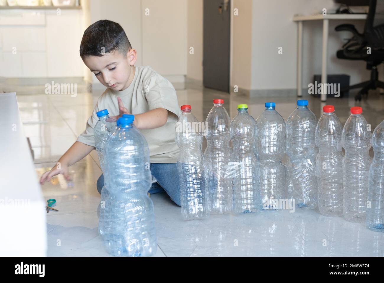 Child build a tower from recycled plastic bottles. Idea uses of old