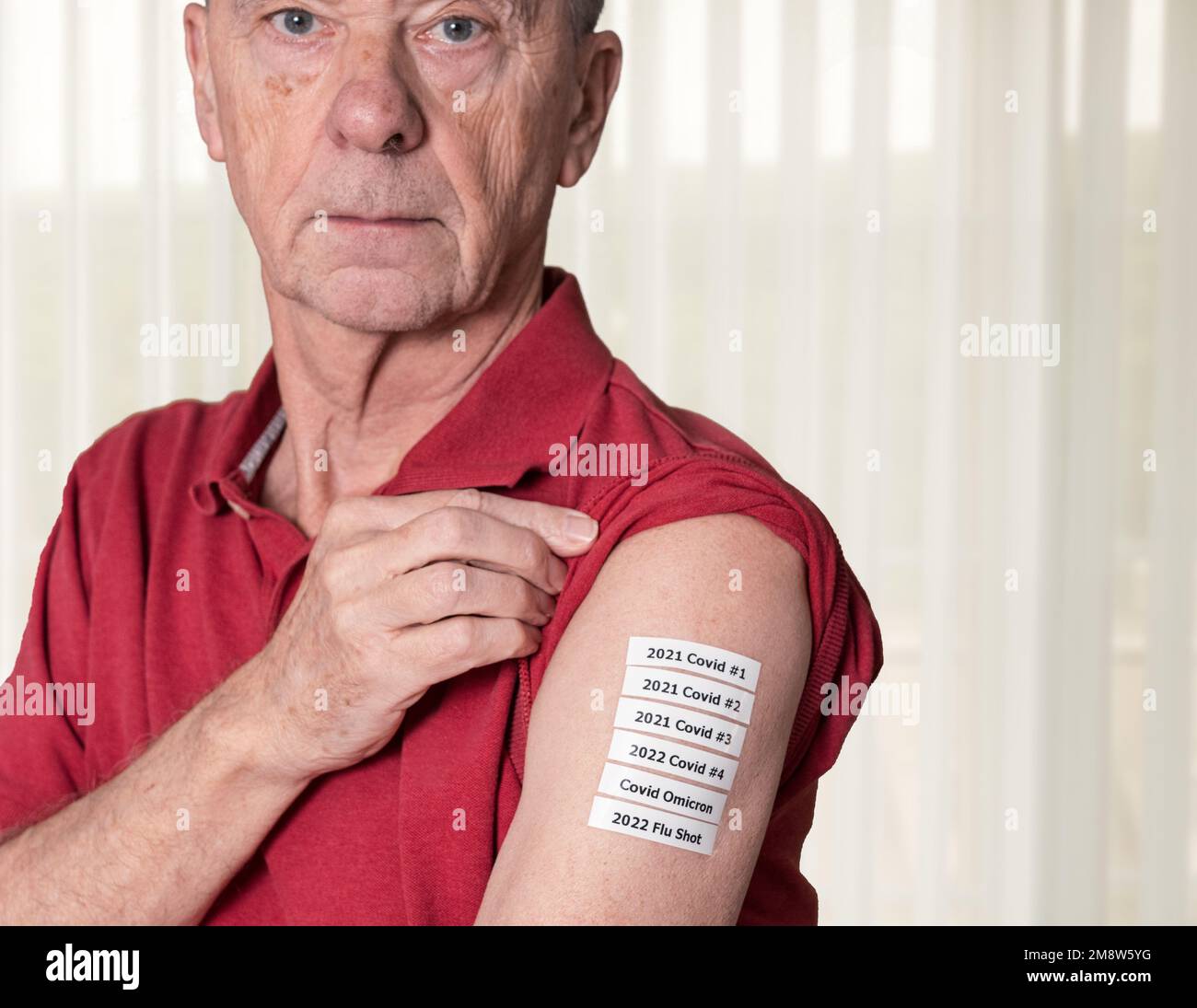 Senior adult man showing all the Covid and flu shots or vaccinations in his shoulder during the pandemic Stock Photo