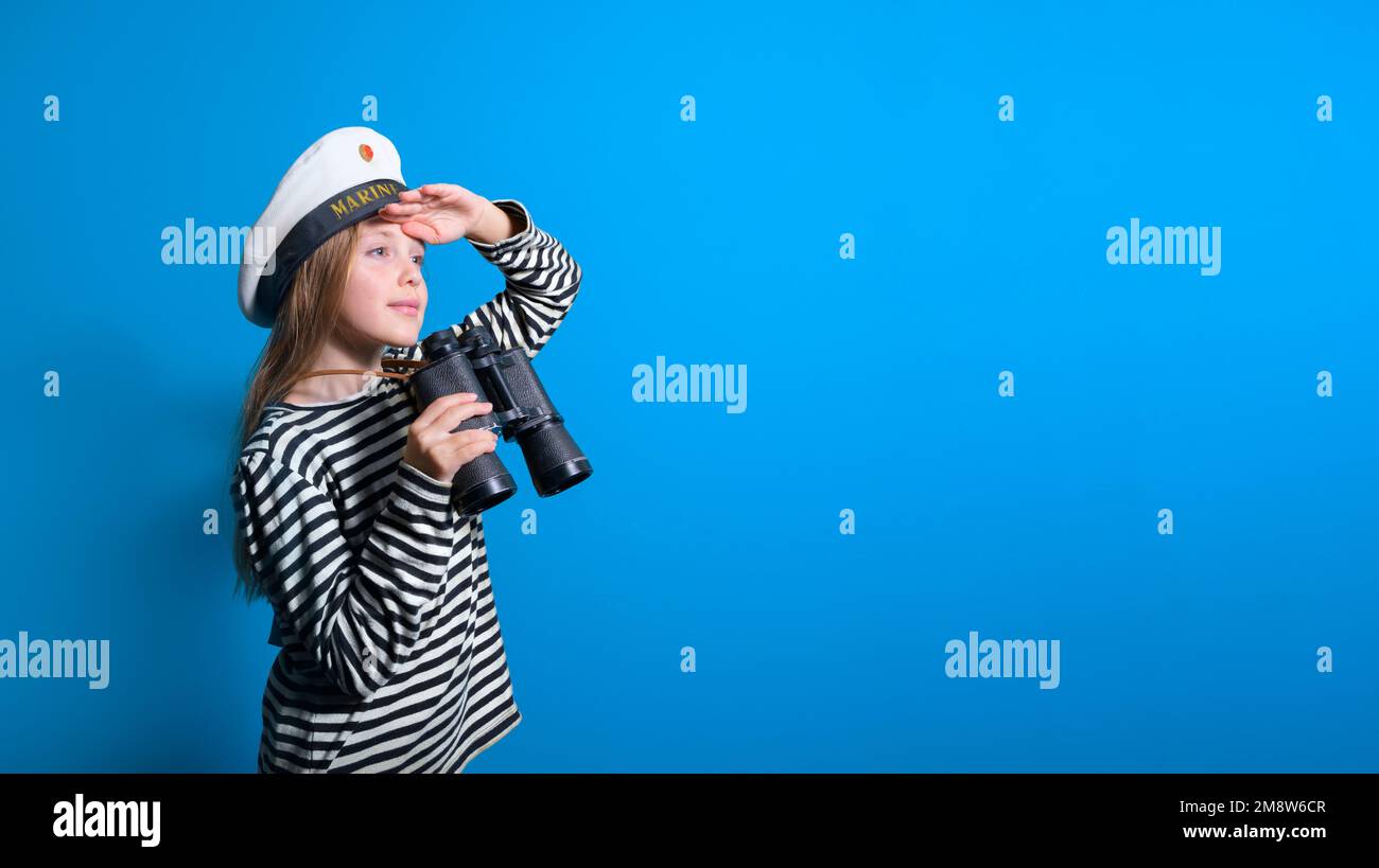 Banner of a sailor girl on a blue background teenage girl in a sailor suit with a binocular looking into the distance Stock Photo