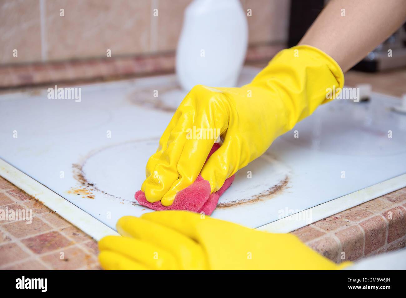 Man cleaning ceramic modern stove or hob with detergent agent. Hand in