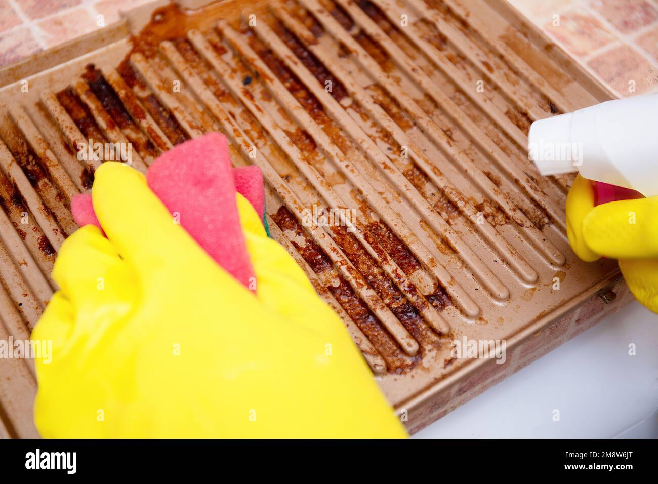 Man cleaning grilled pan or electric grill with detergent agent. Hands