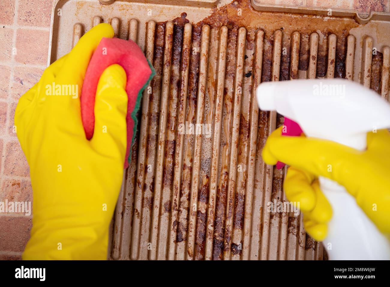 Man cleaning grilled pan or electric grill with detergent agent. Hands