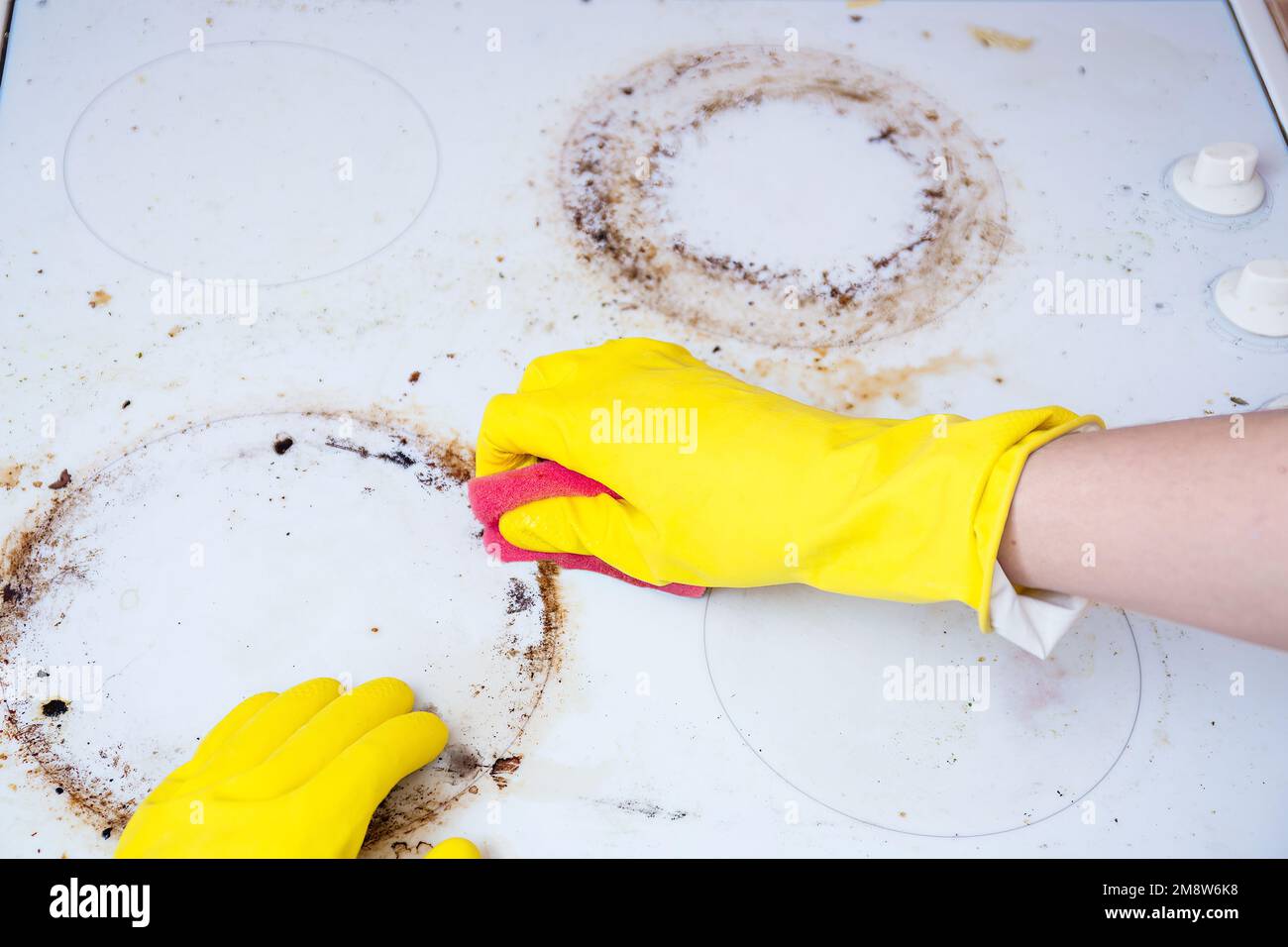 Man cleaning ceramic modern stove or hob with detergent agent. Hand in