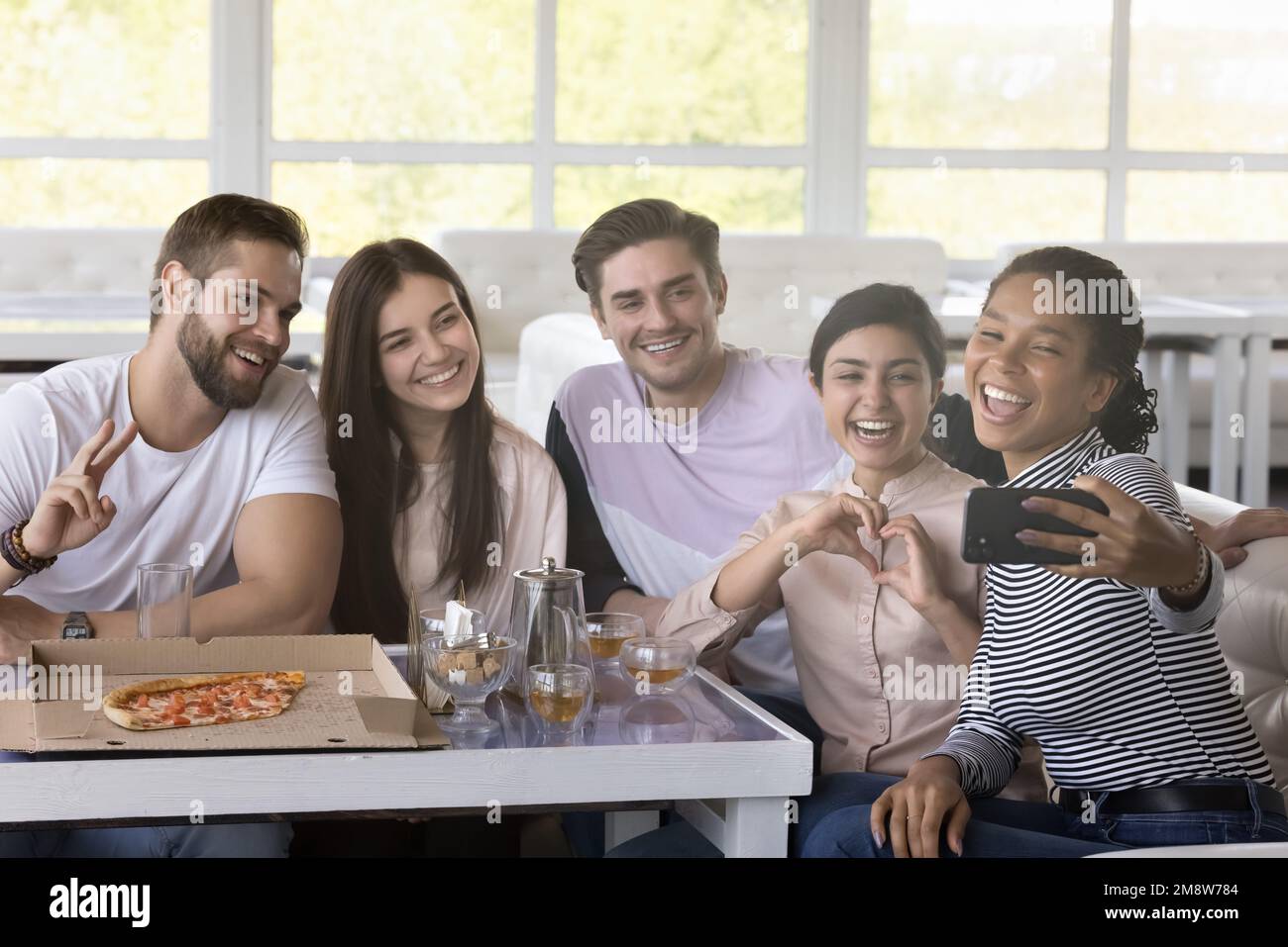 Happy multiethnic friends taking selfie on smartphone in cafe Stock Photo
