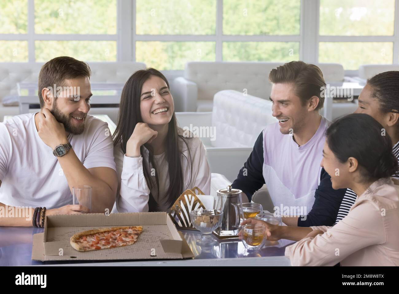 Happy joyful young friends having fun in pizzeria Stock Photo