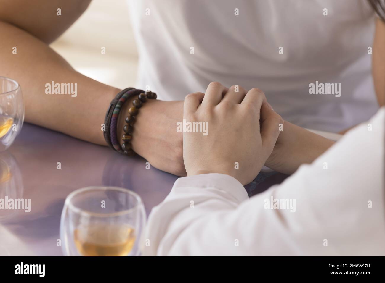 Young couple holding hands over tabletop, meeting in cafe Stock Photo