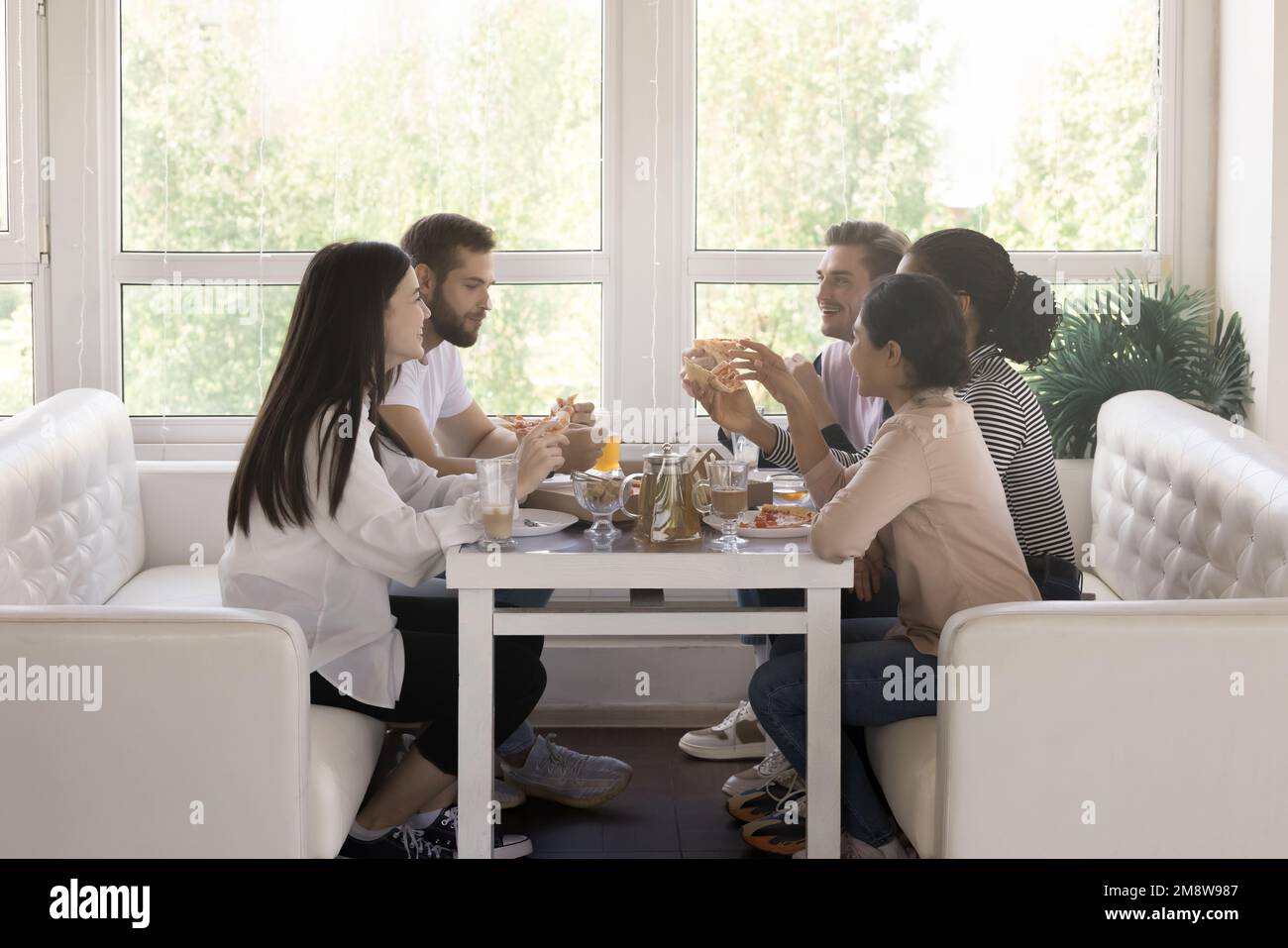 Group of young friends meeting for dinner in cafe together Stock Photo