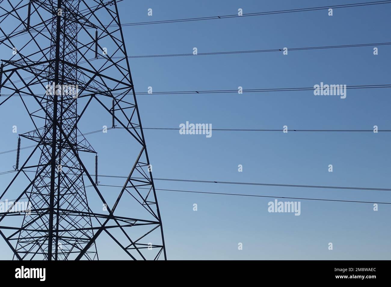 Overhead power line structures and electrical cable wires sihouette. Stock Photo