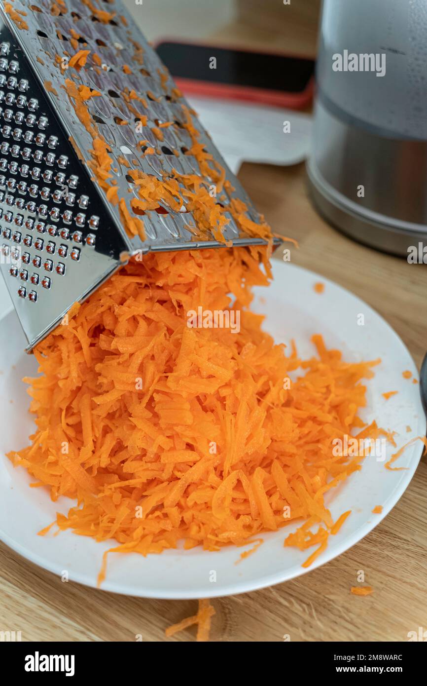 Chef preparing food, using a grating kitchen utensil to grate a carrot Stock Photo