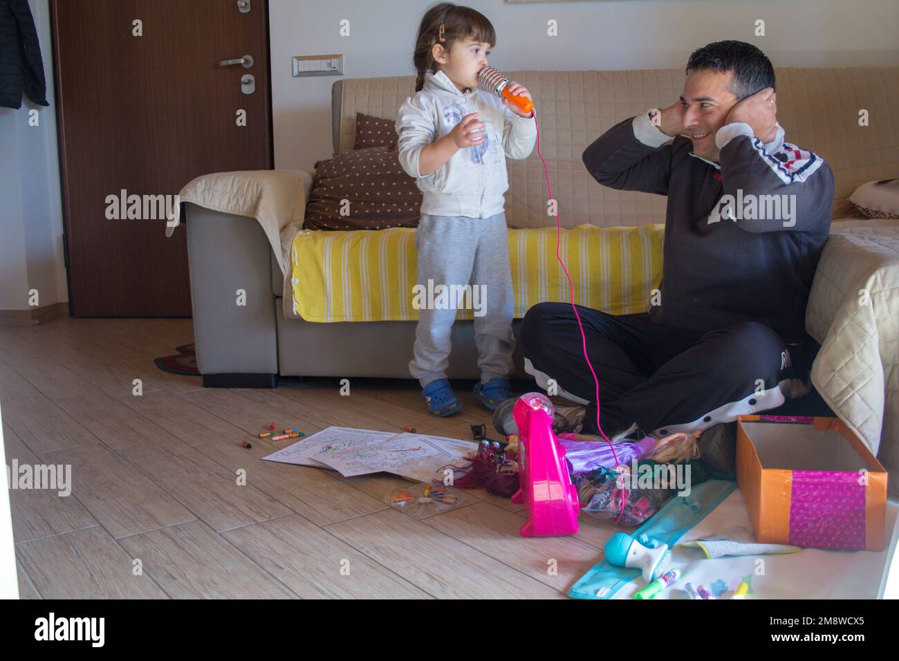 Image of an adorable little girl playing karaoke singing while dad is