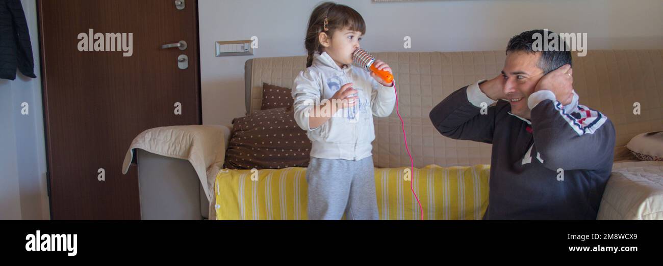 Image of an adorable little girl playing karaoke singing while dad is