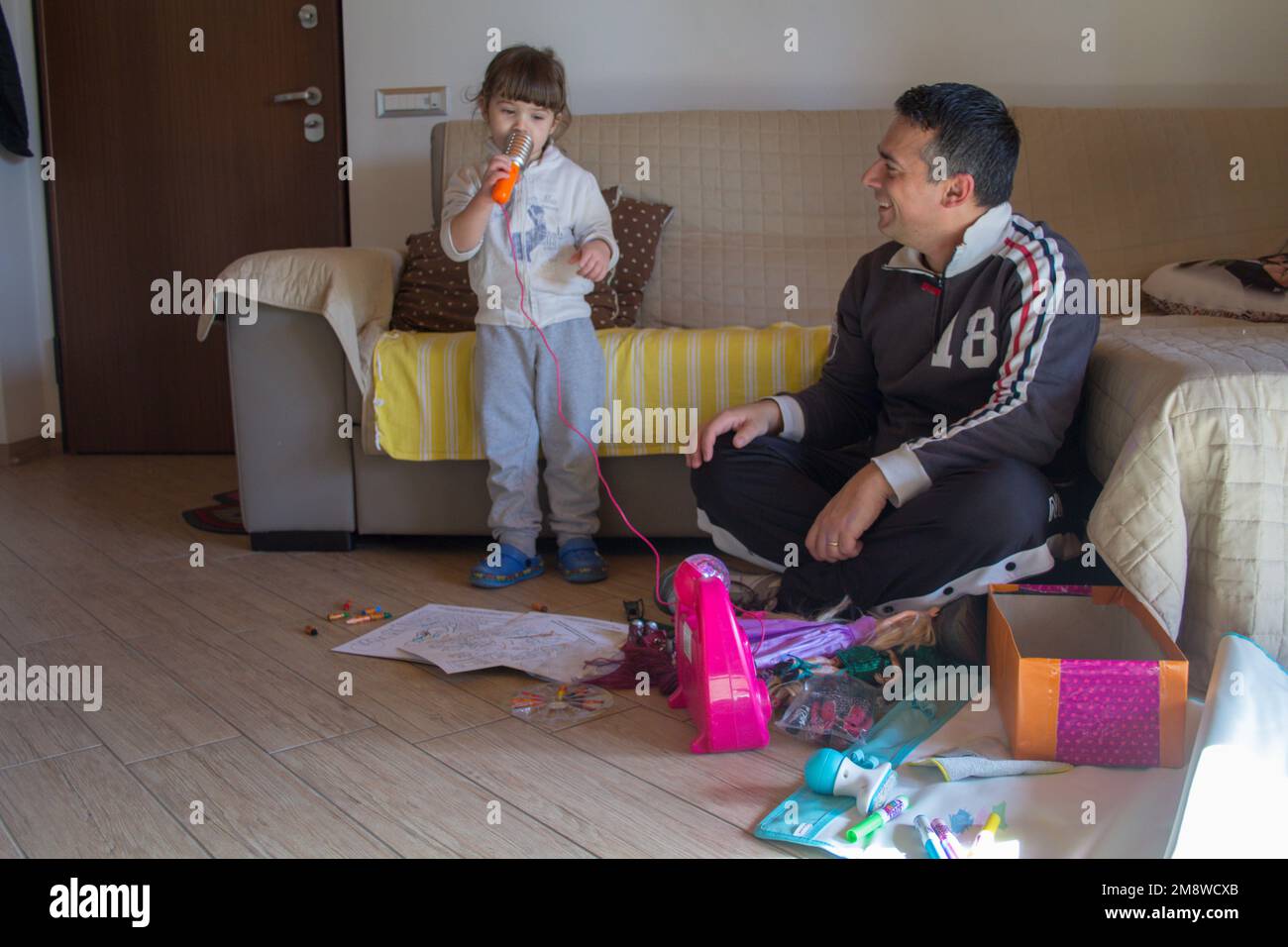 Image of an adorable little girl playing karaoke singing together with