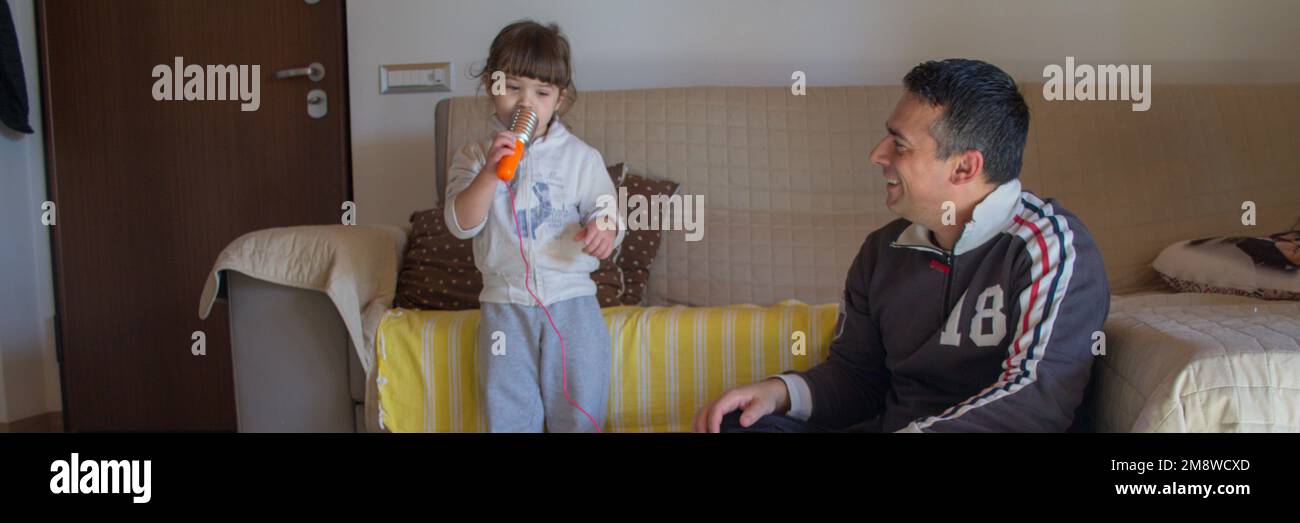 Image of an adorable little girl playing karaoke singing together with