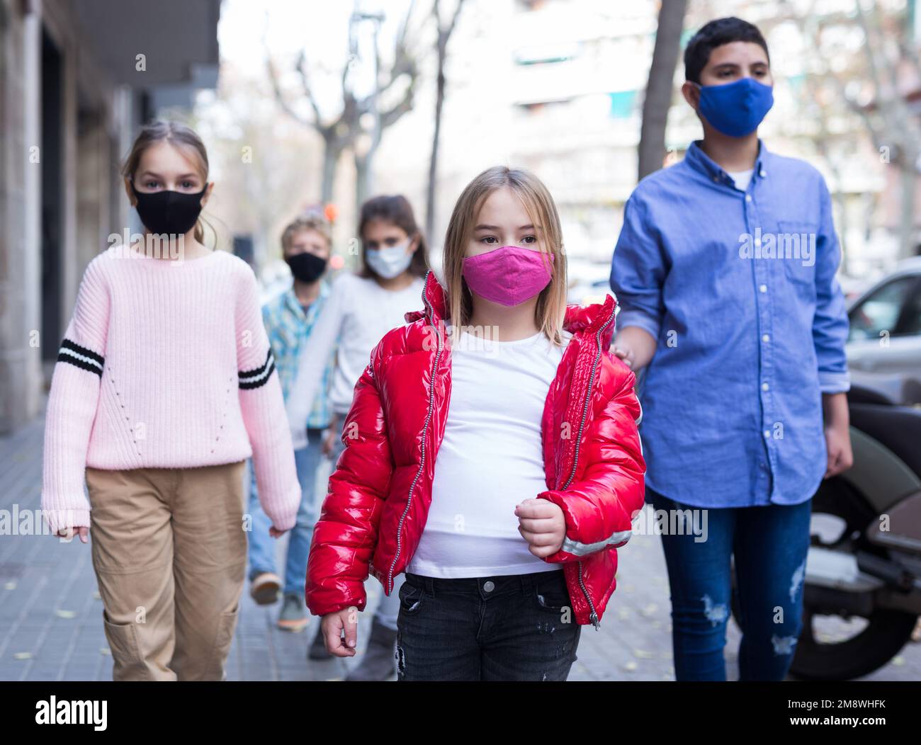 Children in a protective mask going to shool down city street Stock Photo