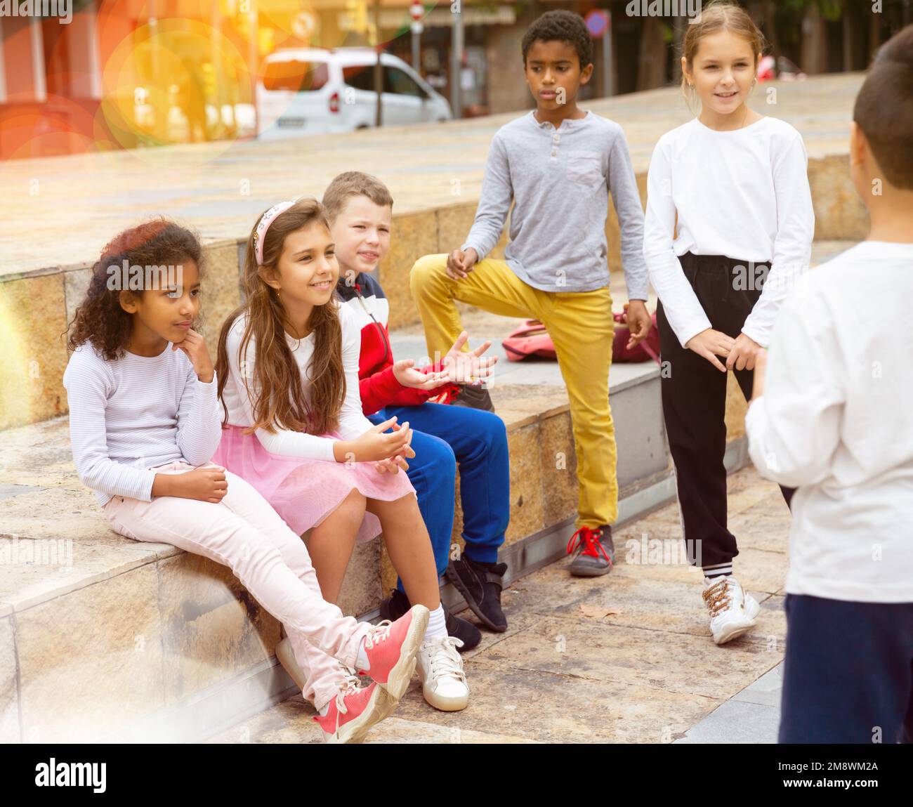 Children during conversation sitting on stairs outdoors Stock Photo