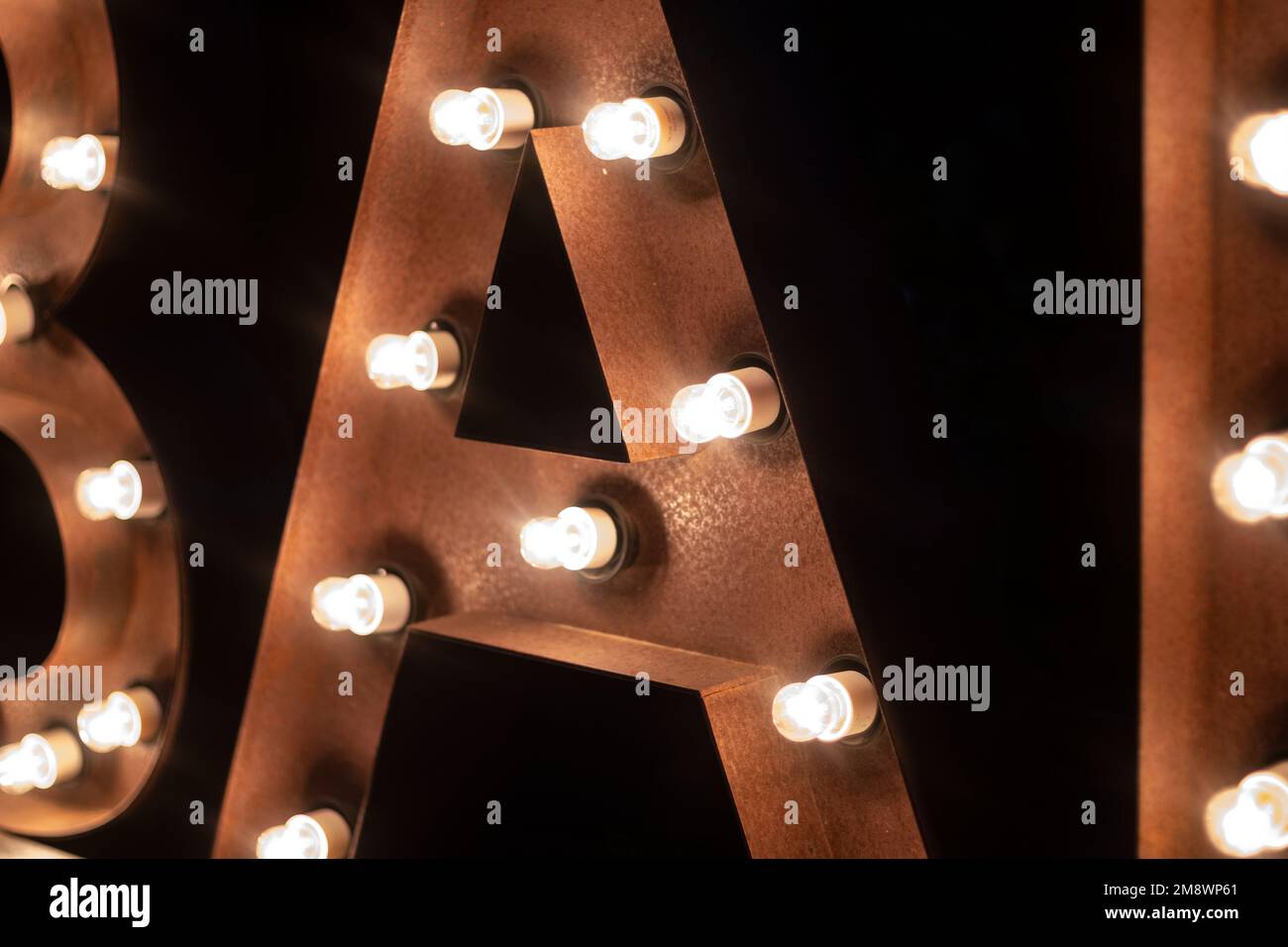 B A R letters lighted by spotlights on a dark black background Stock Photo