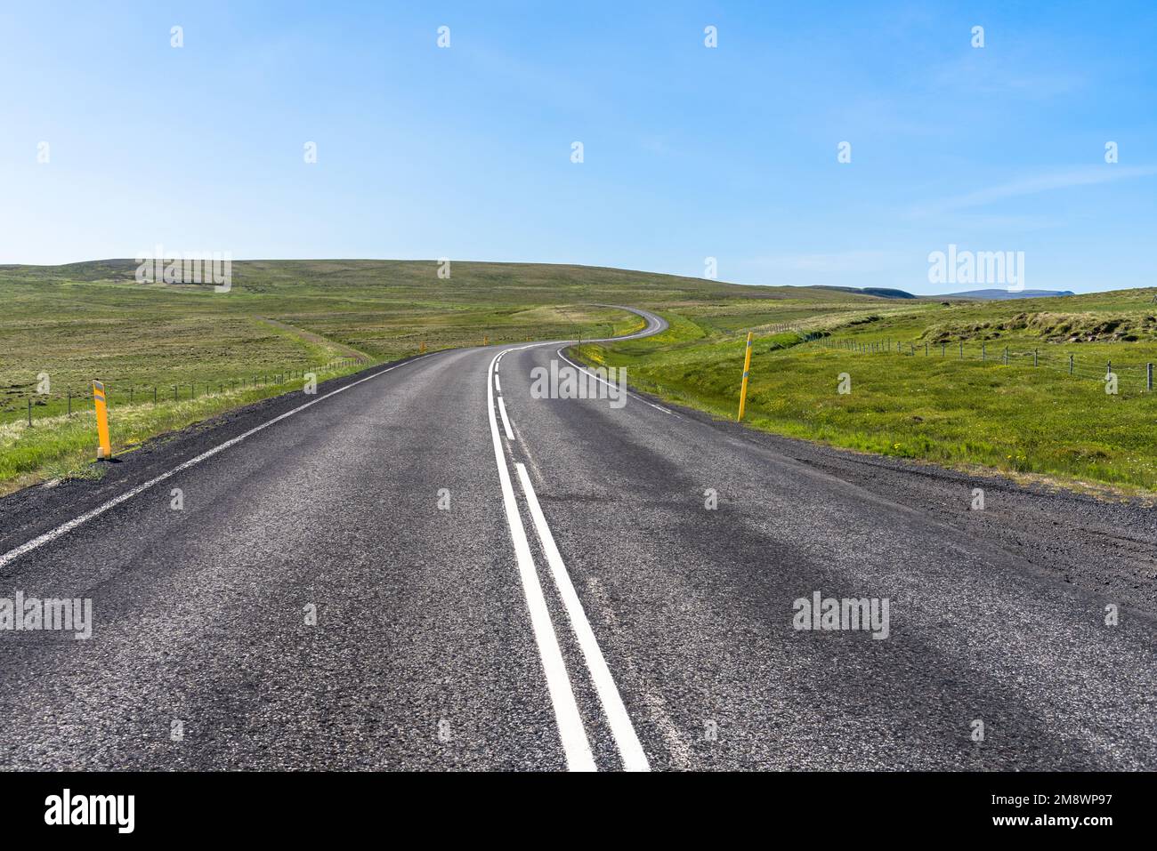 Deserted winding road through grassy hills in Iceland on a clear summer day Stock Photo